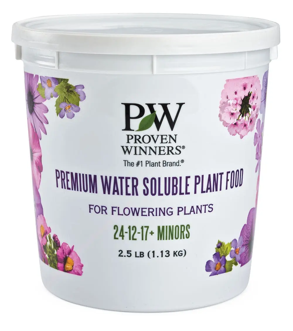 A white tub of "Proven Winners Premium Water Soluble Plant Food" for flowering plants, 24-12-17 formula, 2.5 lb, decorated with purple and pink flowers.